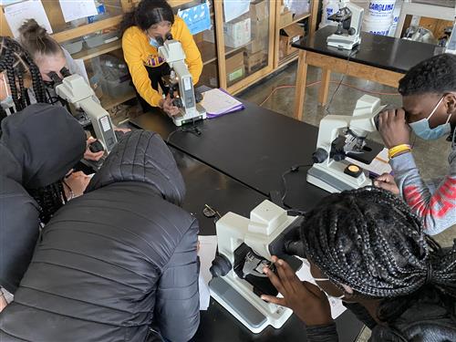 Students gathered around microscopes.